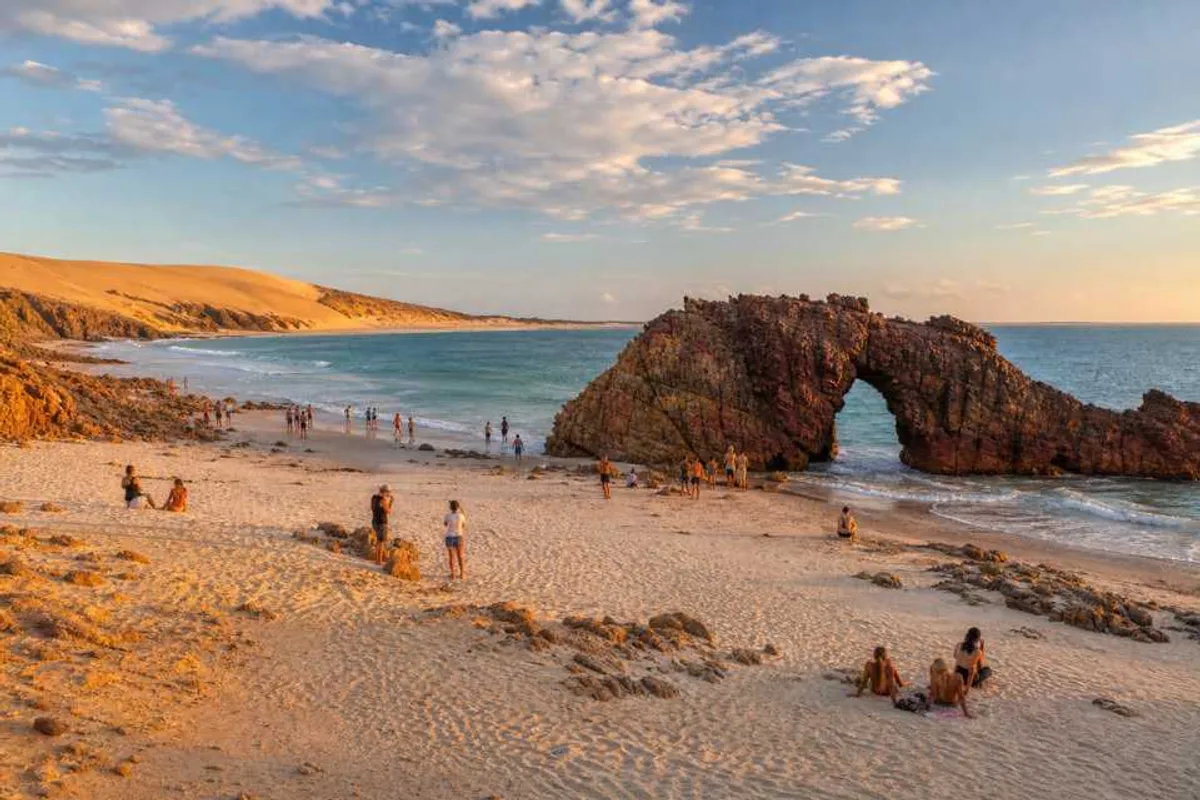 Praia de Jericoacoara ao pôr do sol com a Pedra Furada e dunas de areia
